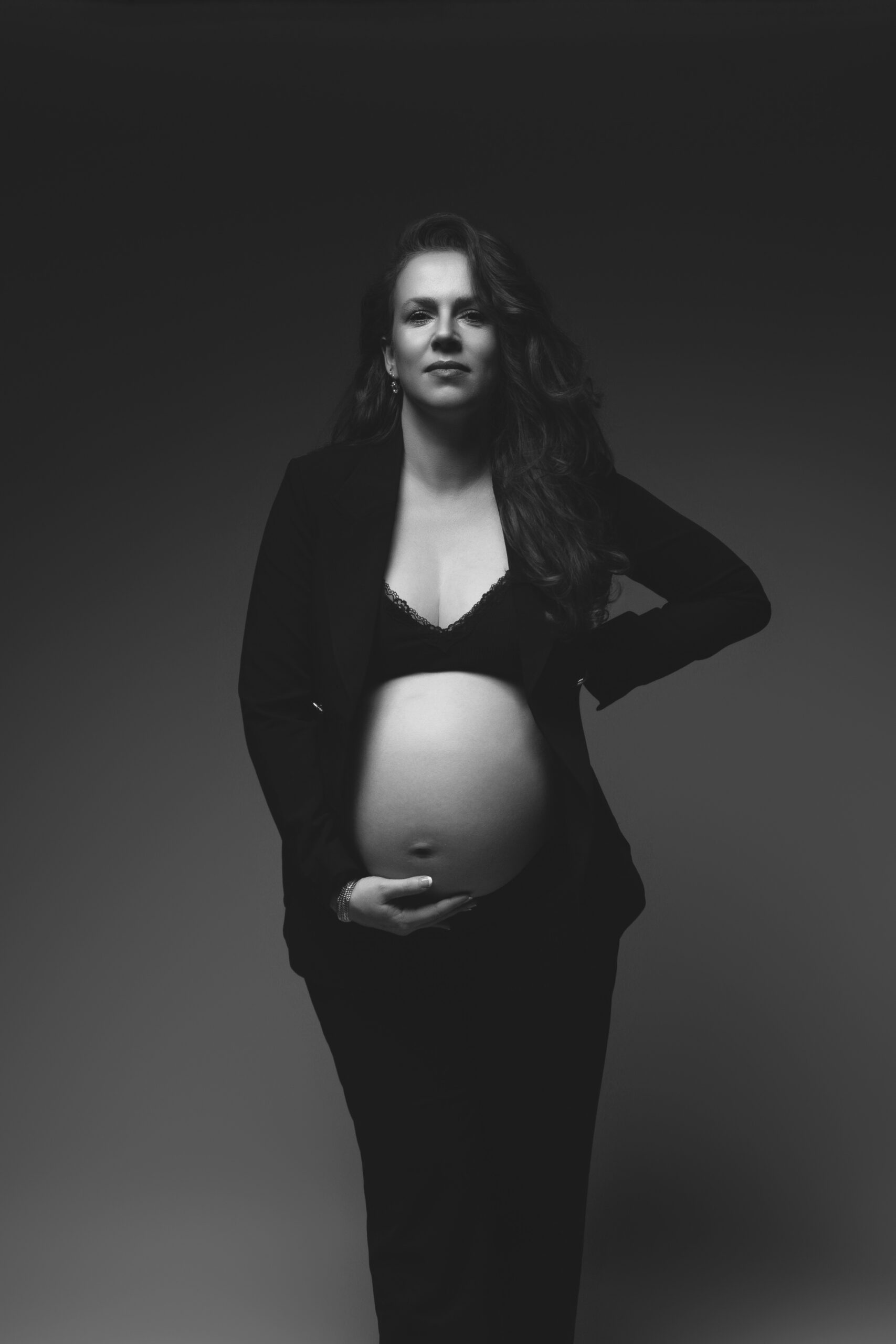 Zwangere vrouw tijdens studio zwangerschapsfotografie in zwart-wit